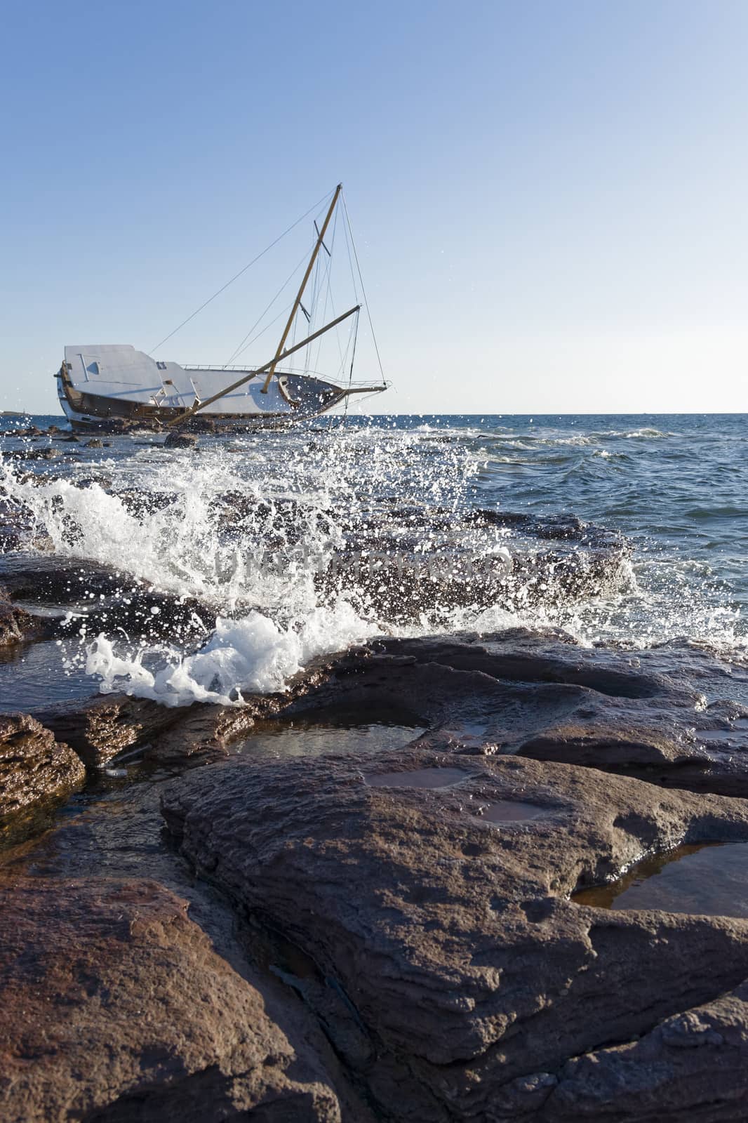 Sailboat, stranded along the coast on the cliff of Sardinia in the Mediterranean Sea.