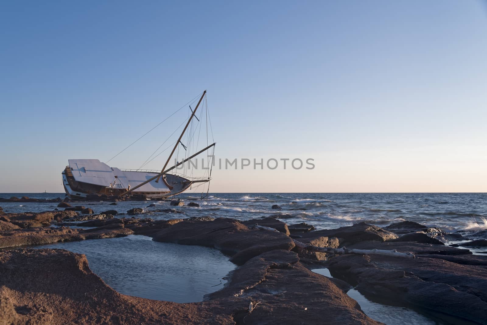 Sailboat, stranded along the coast on the cliff of Sardinia in the Mediterranean Sea.