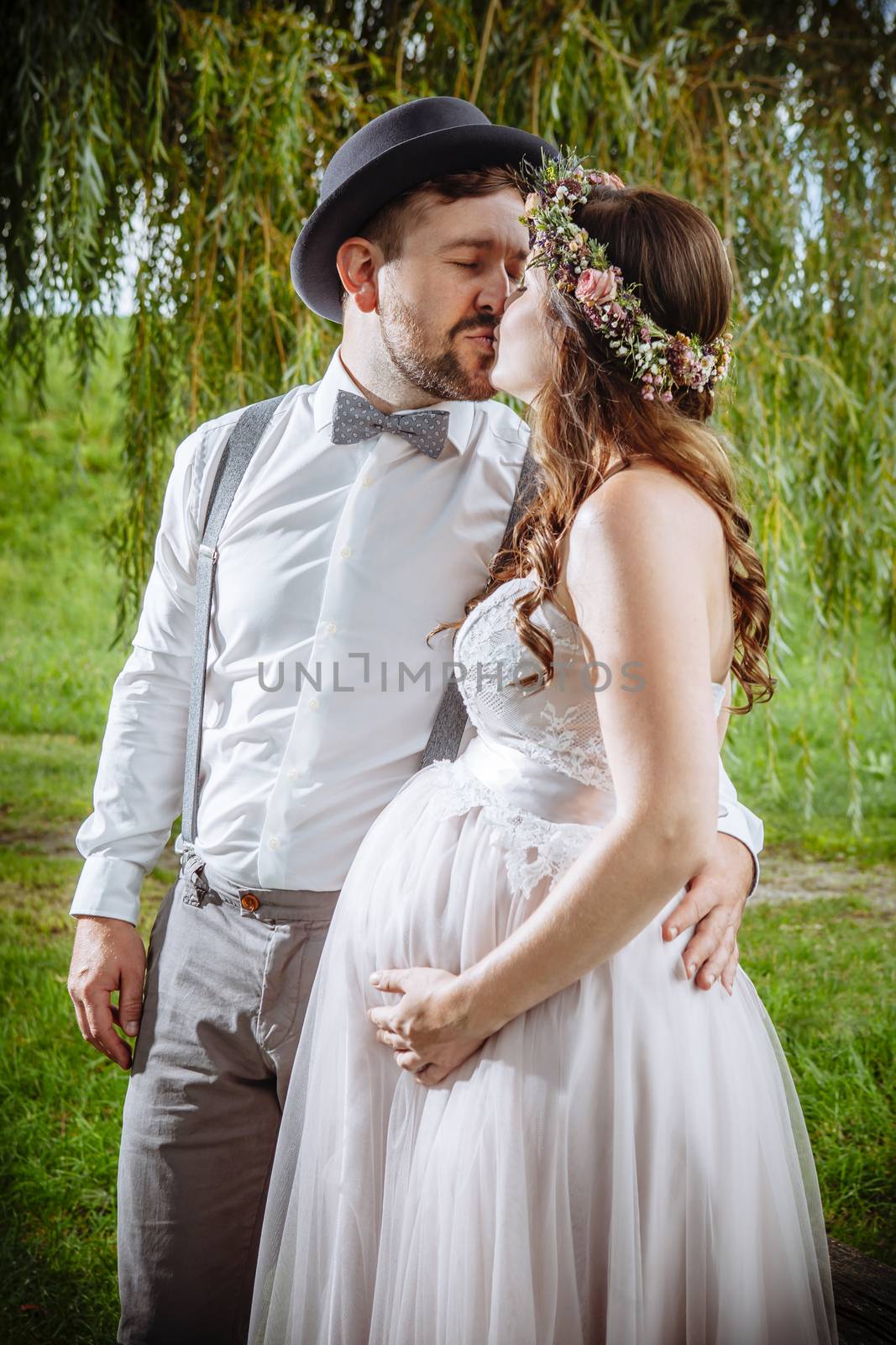 Photo of a pregnant bride and groom kissing during the wedding ceremony.
