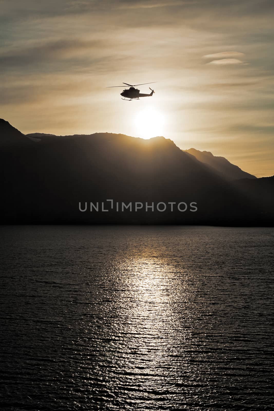 Helicopter flying over the sea at sunset by LuigiMorbidelli