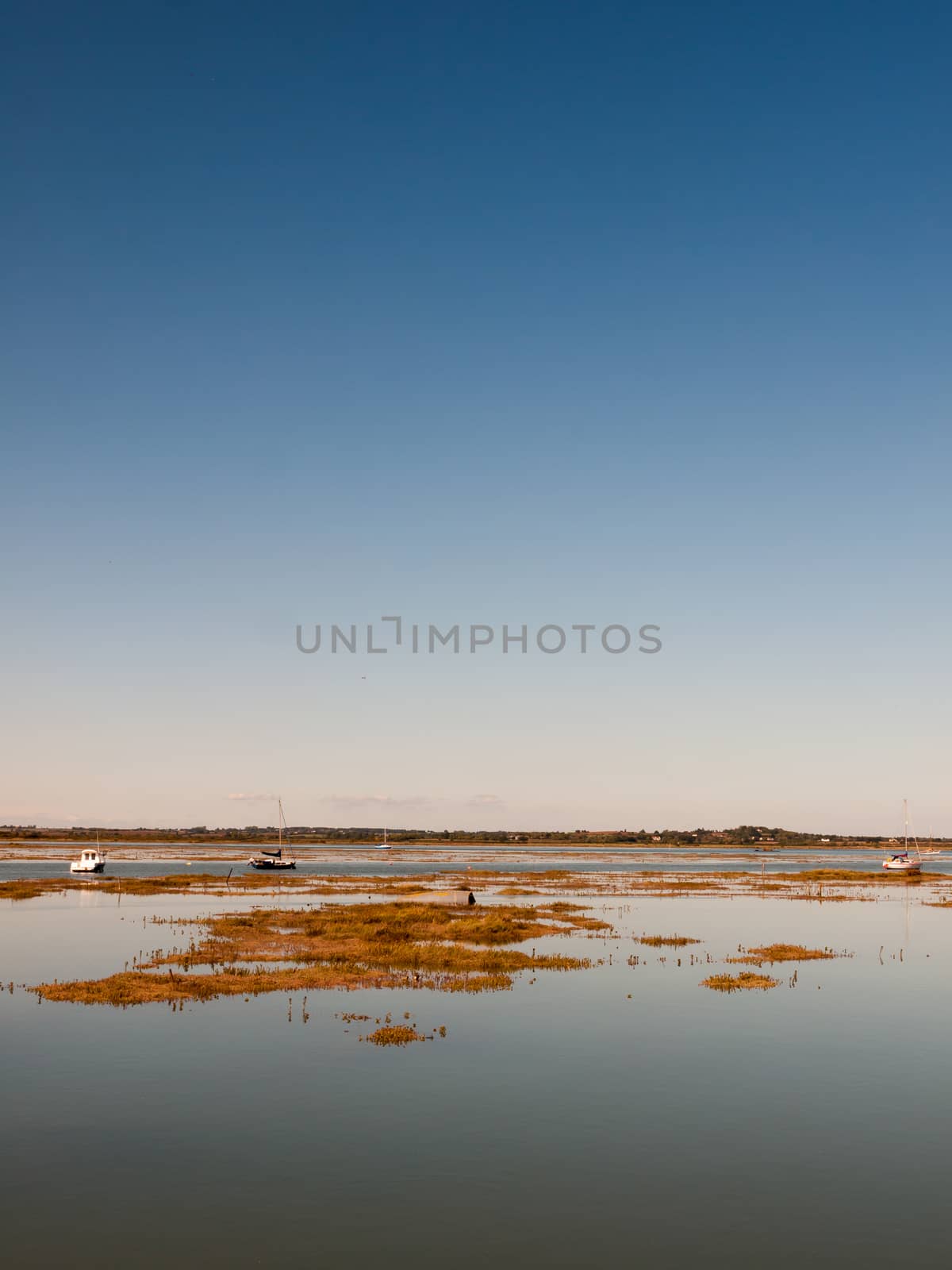 peaceful blue space river estuary scene outside bright sunny day boats moored; essex; england; UK