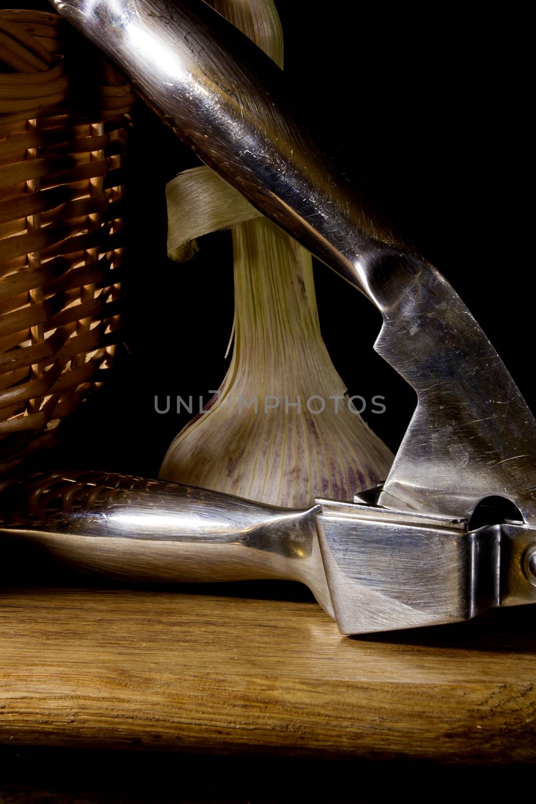 Garlic press and cloves of garlic laid on a wooden table background