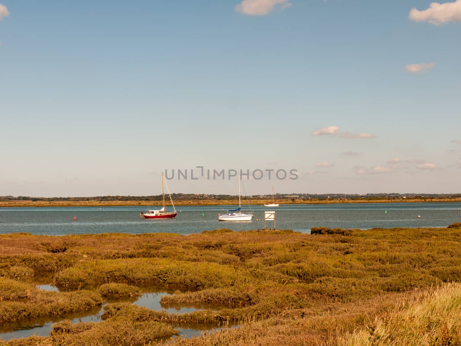 beautiful scene of river with boats grassland in front blue sky and clouds; essex; england; UK