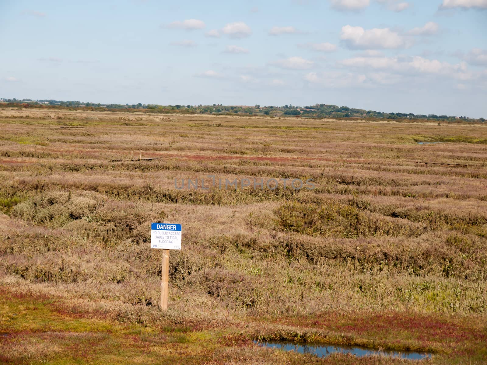 marshland scene outside with danger sign up front; essex; england; UK