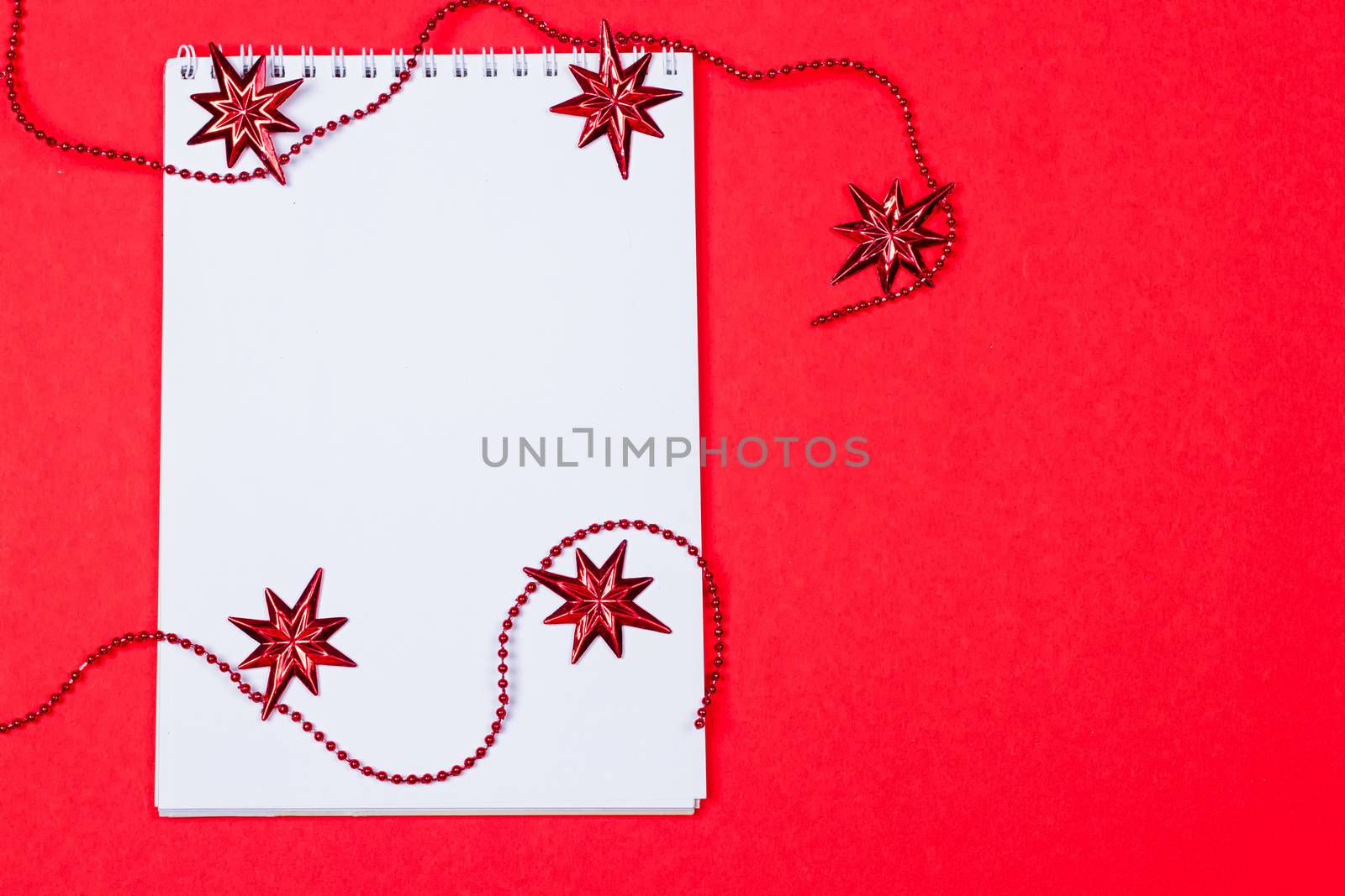 Holiday decorations and notebook on red background