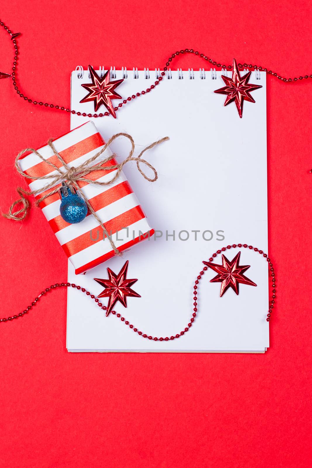 Holiday decorations and notebook on red background