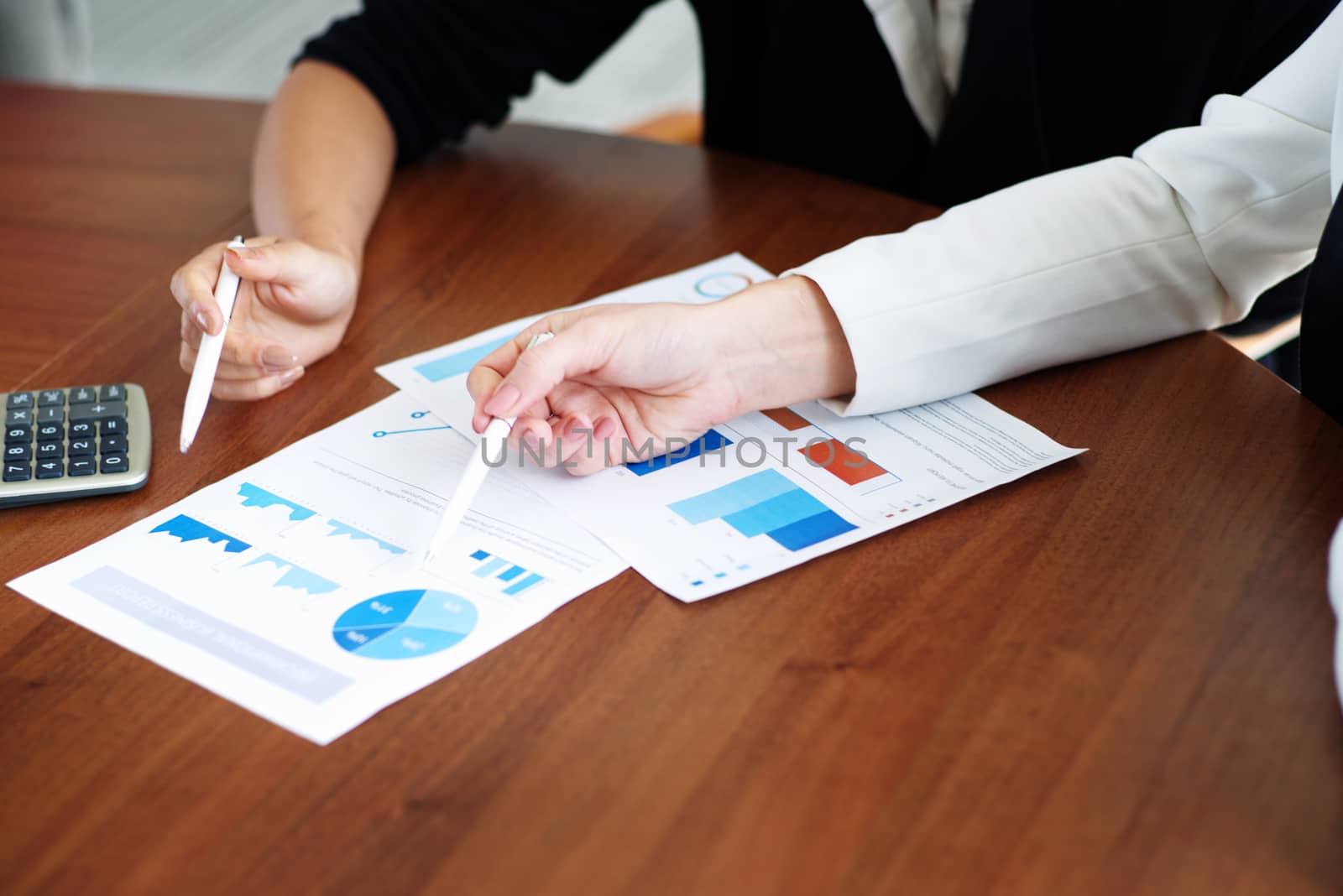 Business people pointing at diagrams discussing financial reports at workplace