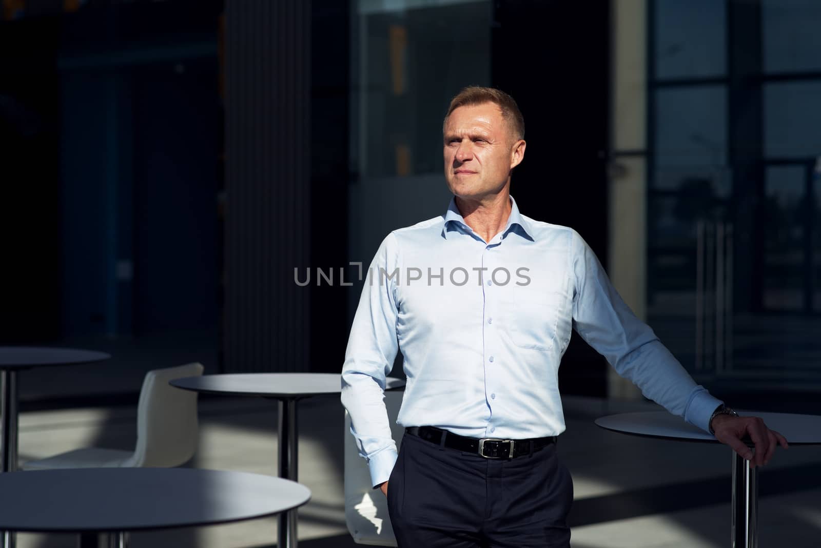 Portrait of serious mature businessman standing in cafe of office building