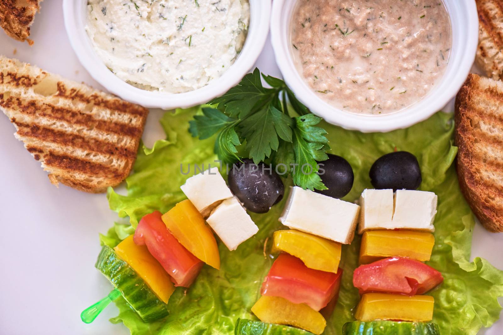 Tasty snacks: roasted toast with cheese vegetables and olive on the stick. Served with two kind of sauce