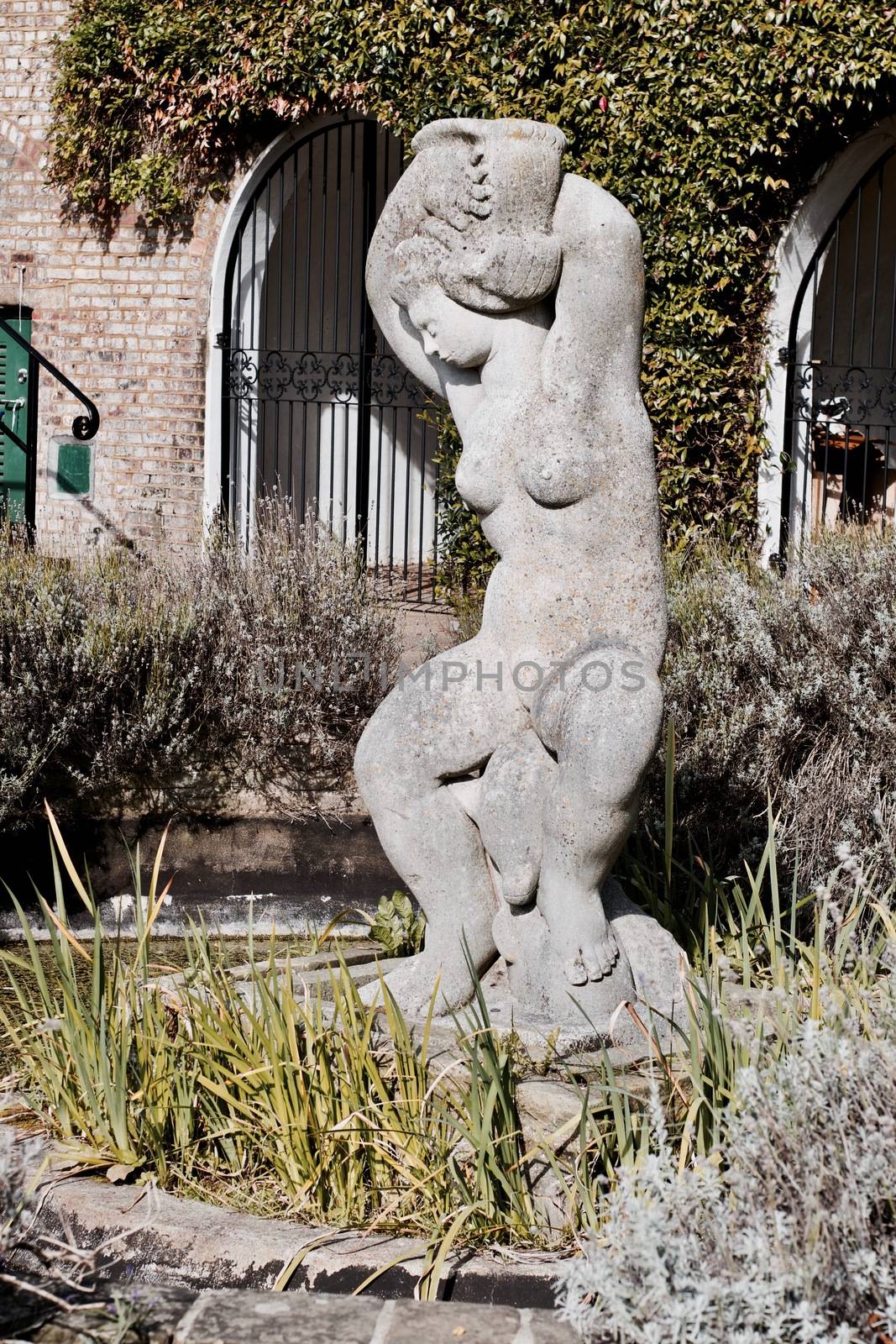 Large woman monument in park near green plants and stones. Richmond, London