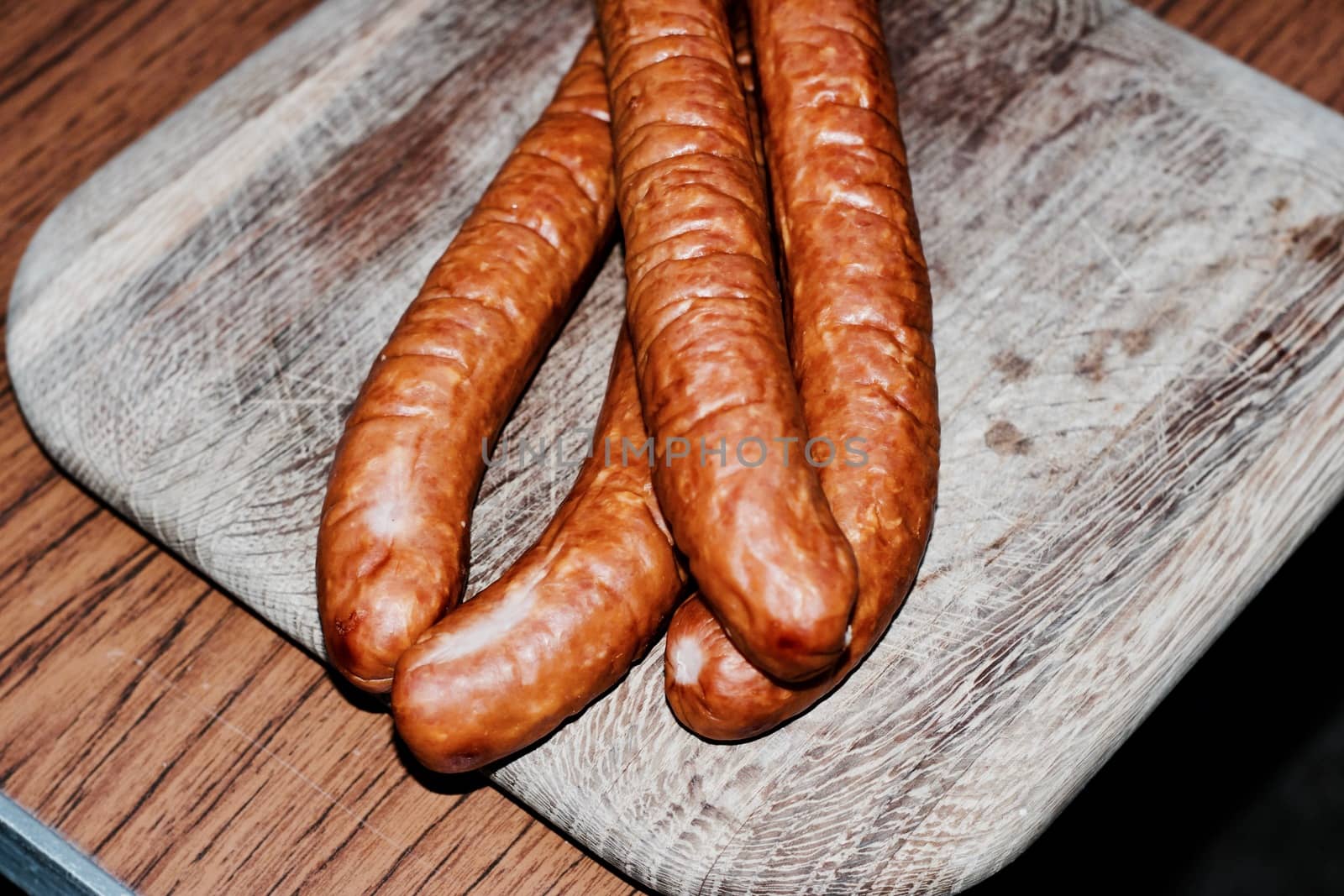 Fresh and tasty sausages on the wooden board. BBQ concept.