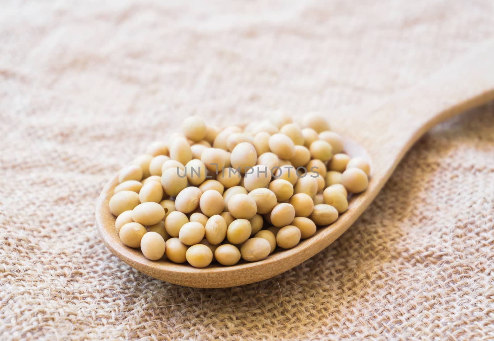 Closeup soy beans on wood spoon with sackcloth background , healthy food concept