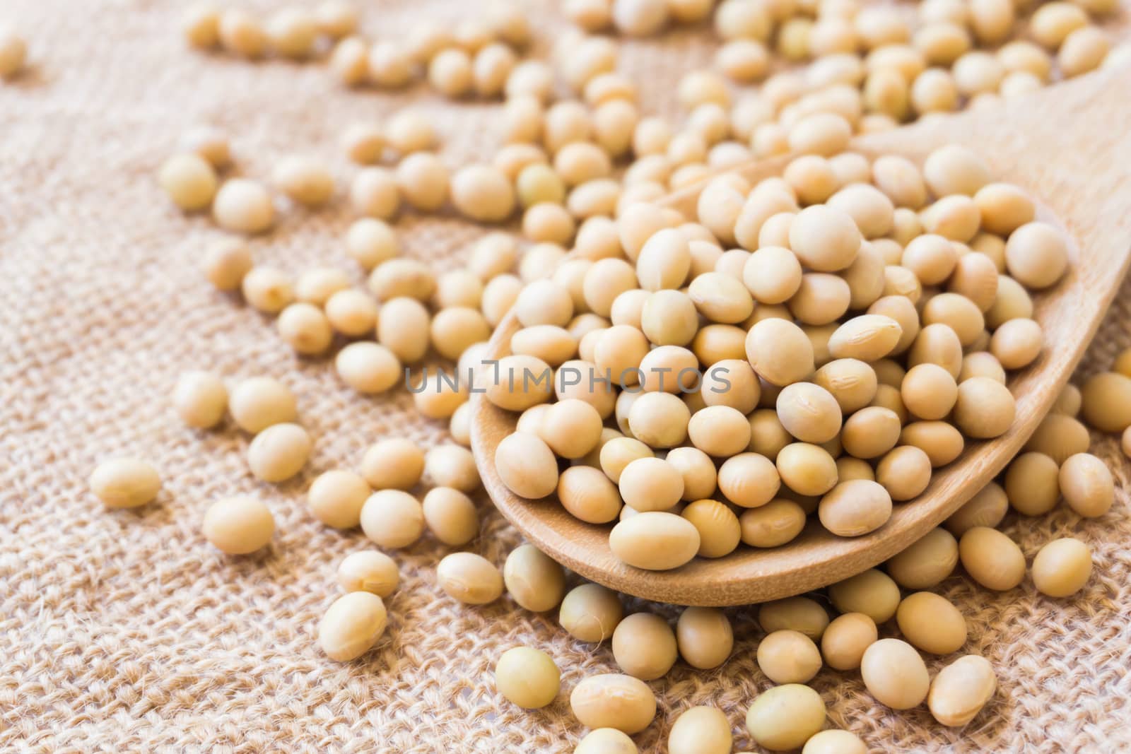Closeup soy beans on wood spoon with sackcloth background , healthy food concept