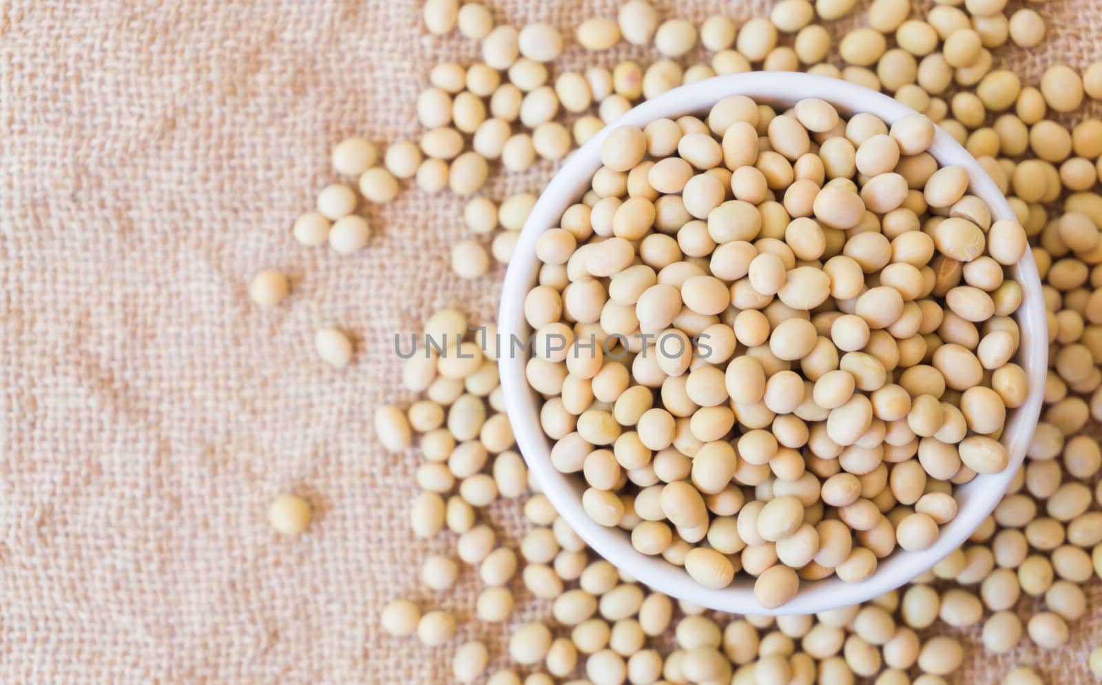 Closeup top view soy beans on white bowl with sackcloth background , healthy food concept