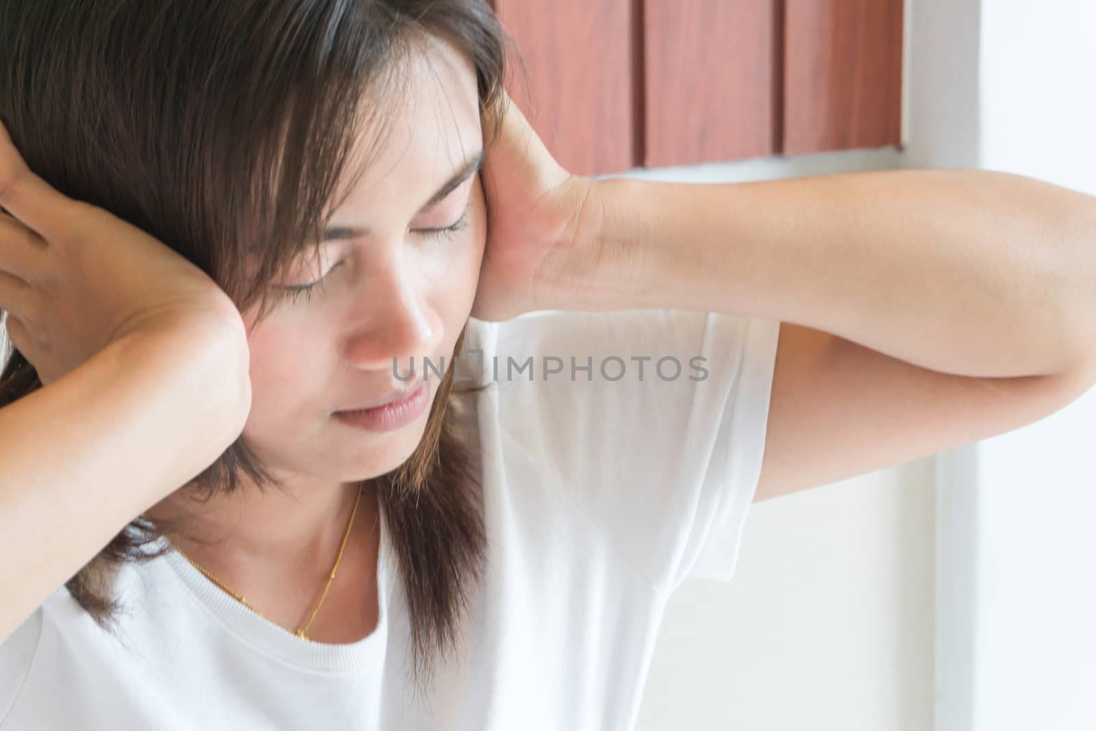Closeup woman hand covering ears in bedroom, health care concept, selective focus