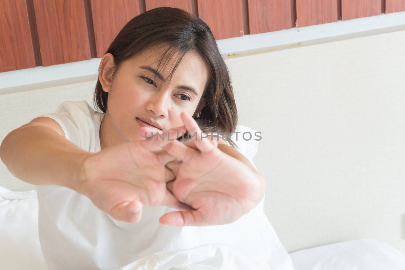 Closeup woman stretching hand on her bed after waking in the morning, selective focus