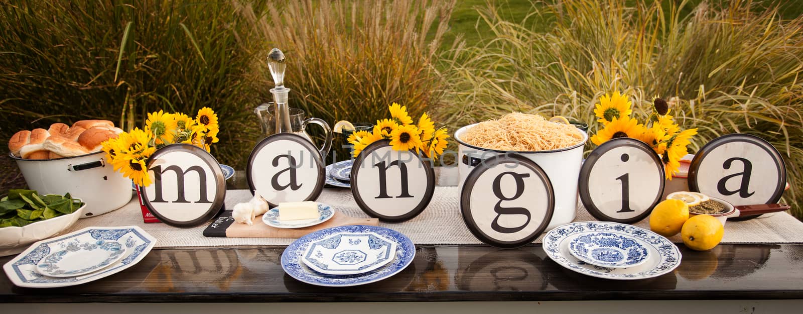 Beautiful rustic table setting with plate letters spelling out the Italian Word "Mangia."
