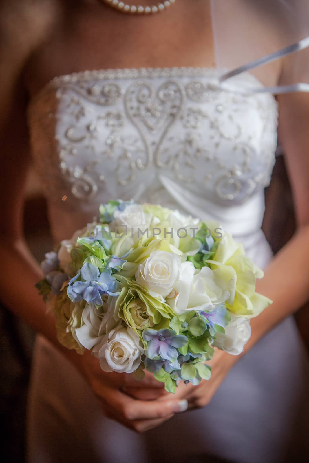 Beautiful bride and groom holding blue, green, white bouquet.