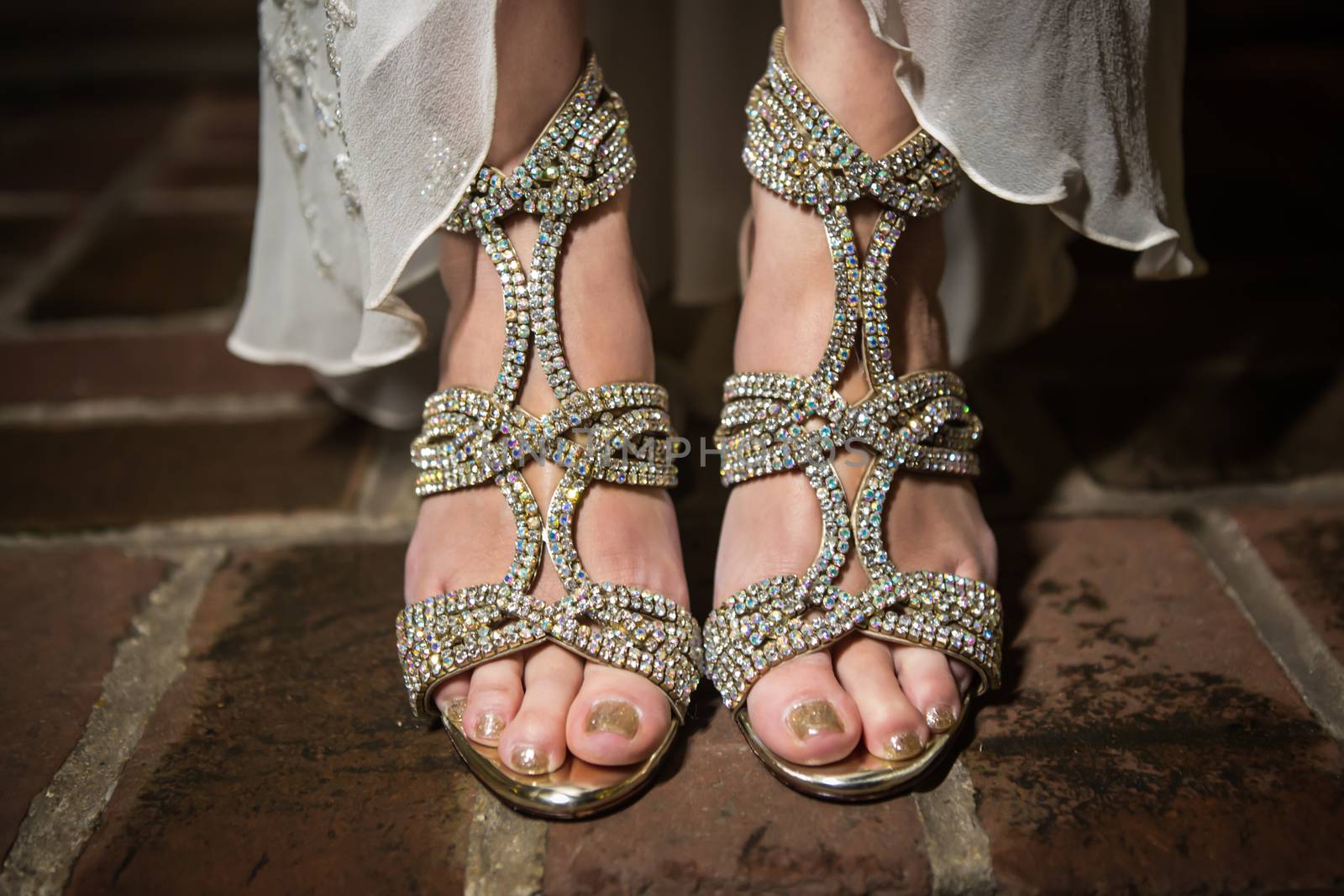 Close Up of Asian bride's  diamond studded shoes standing on a brick floor.