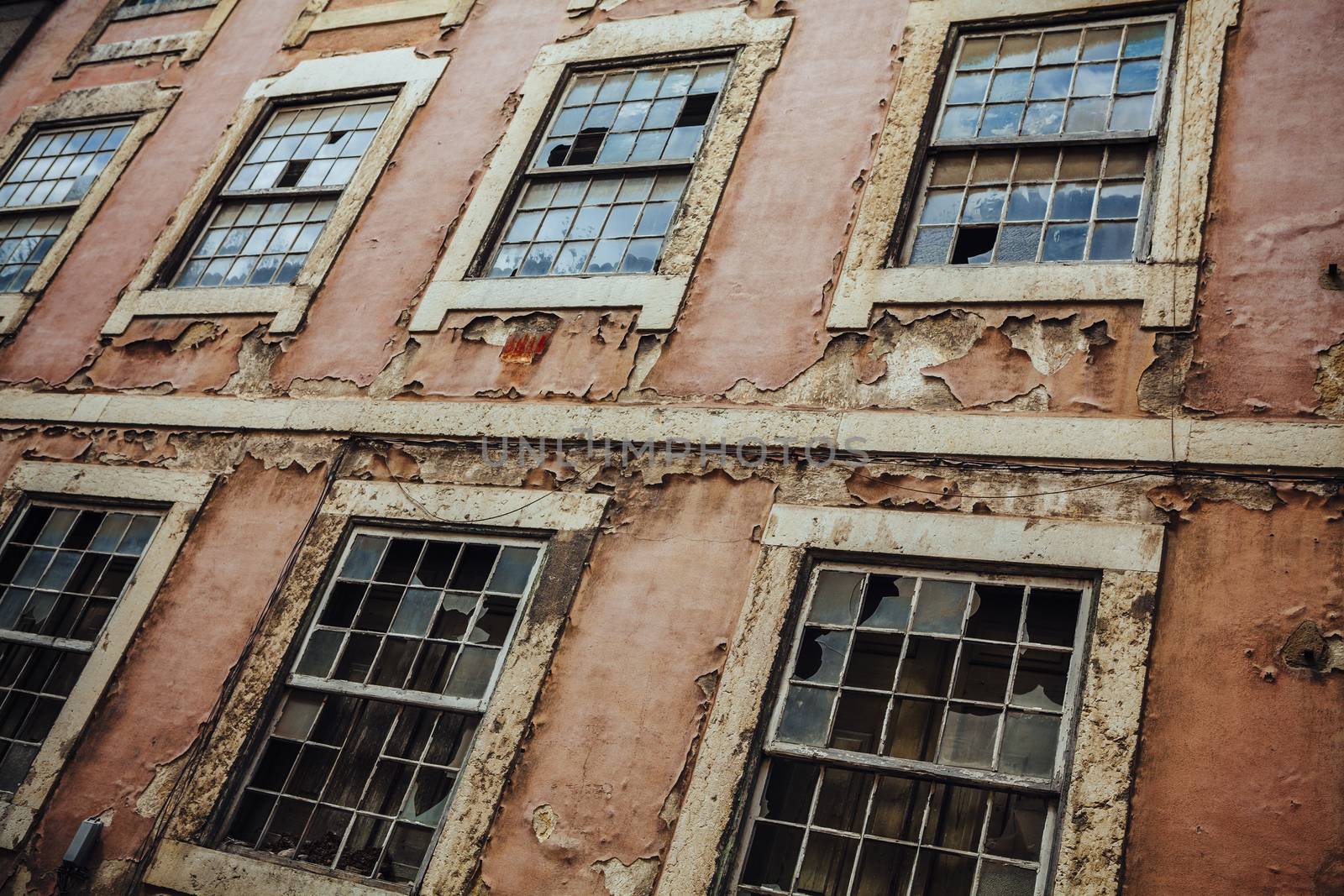 Photo of an old broken building exterior with busted windows and peeling paint.