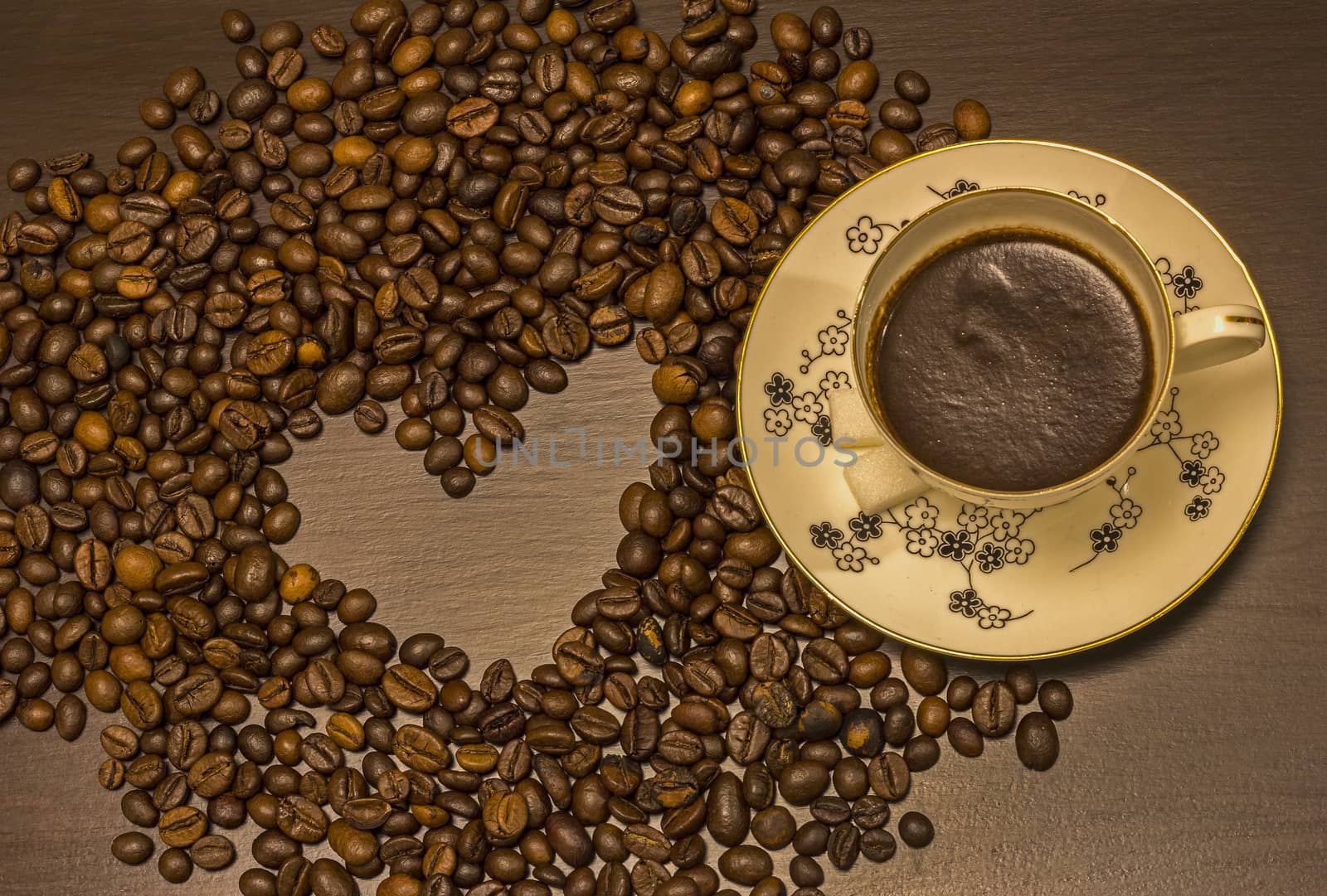 Heart shape made from coffee beans and a cup of coffee on the table