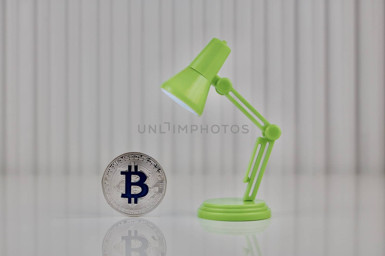 Digital currency physical blue bitcoin coin near green lamp.