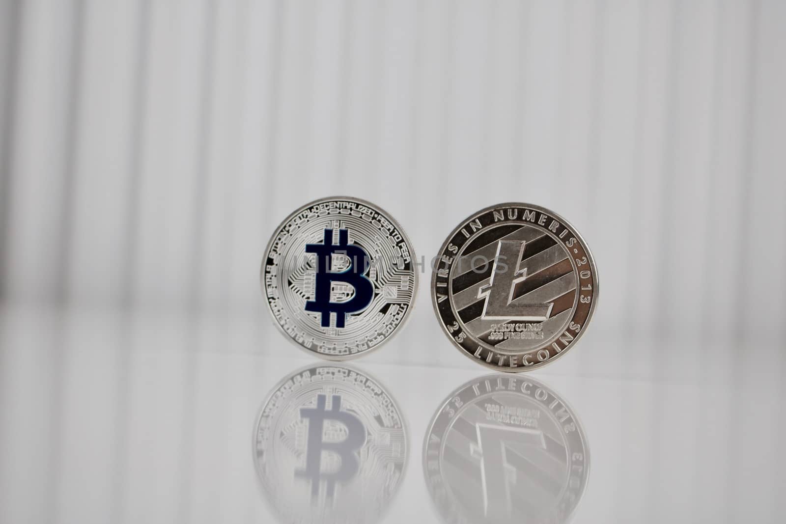 Digital currency physical silver bitcoin and litecoin coins on white table.