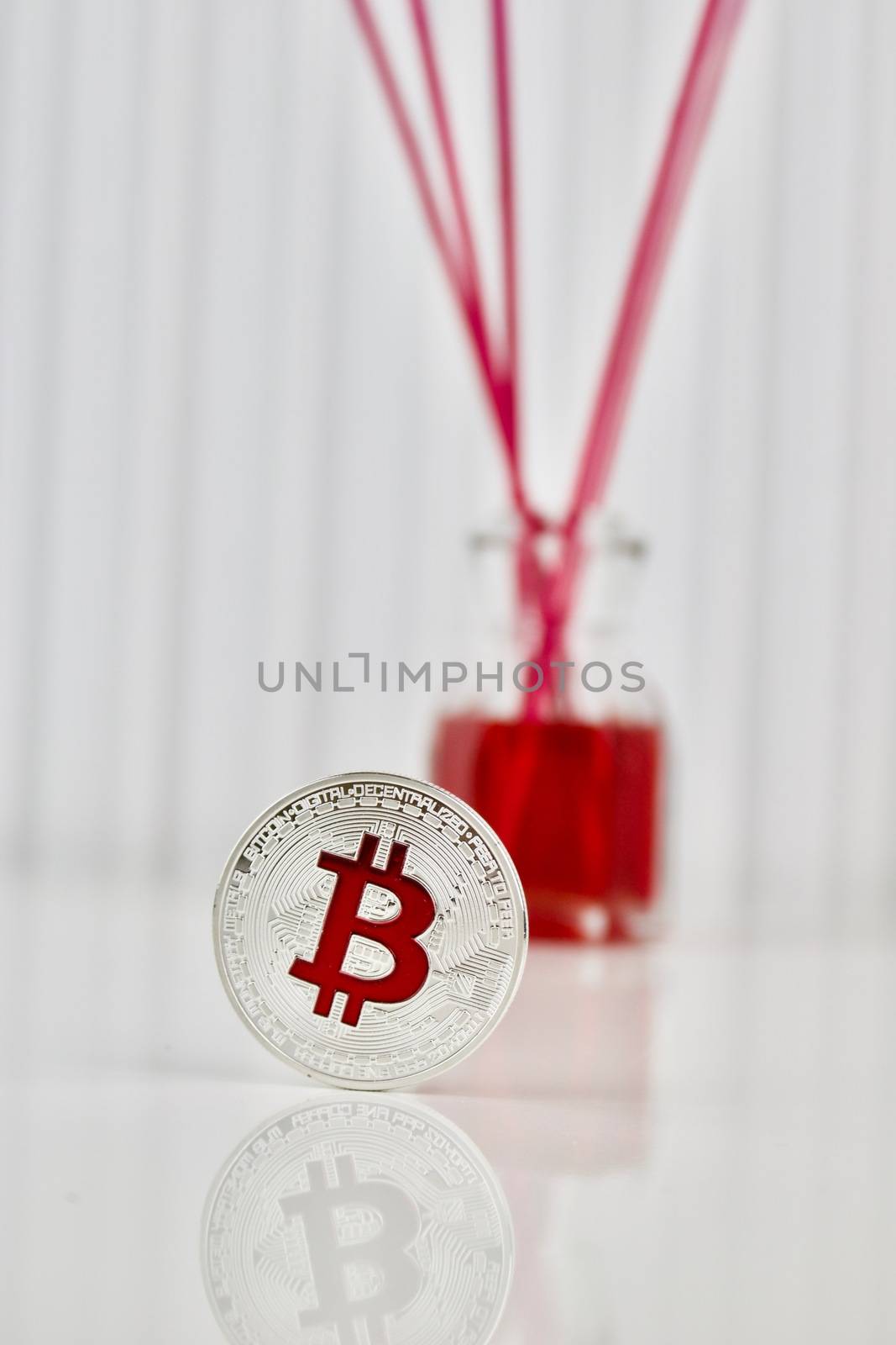 Digital currency physical silver bitcoin coin in red background.