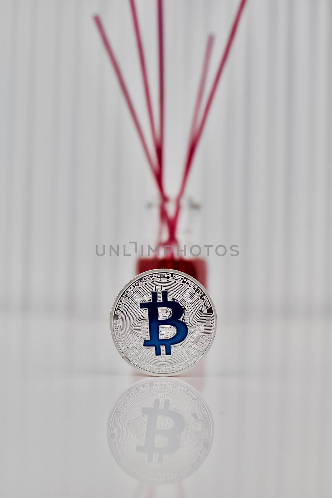 Digital currency physical silver bitcoin coin with blue sign near fragrance.
