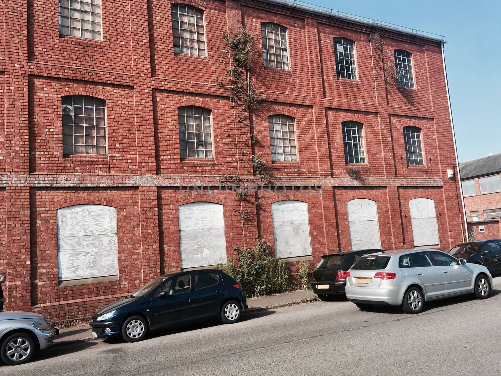 Cars near old brick warehouse with wooden in windows. Newport Pagnell