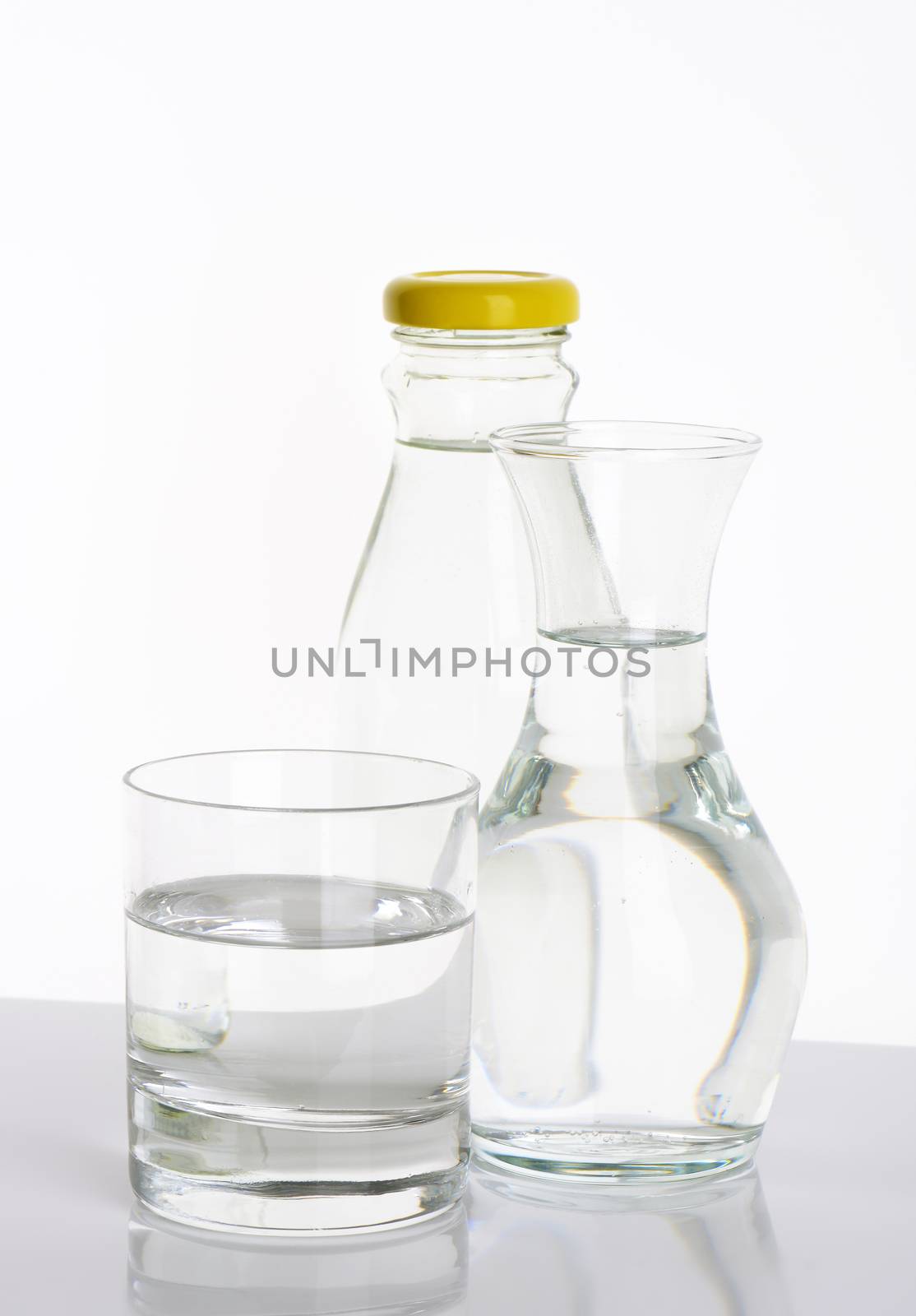 bottle, carafe and glass of fresh water on white background