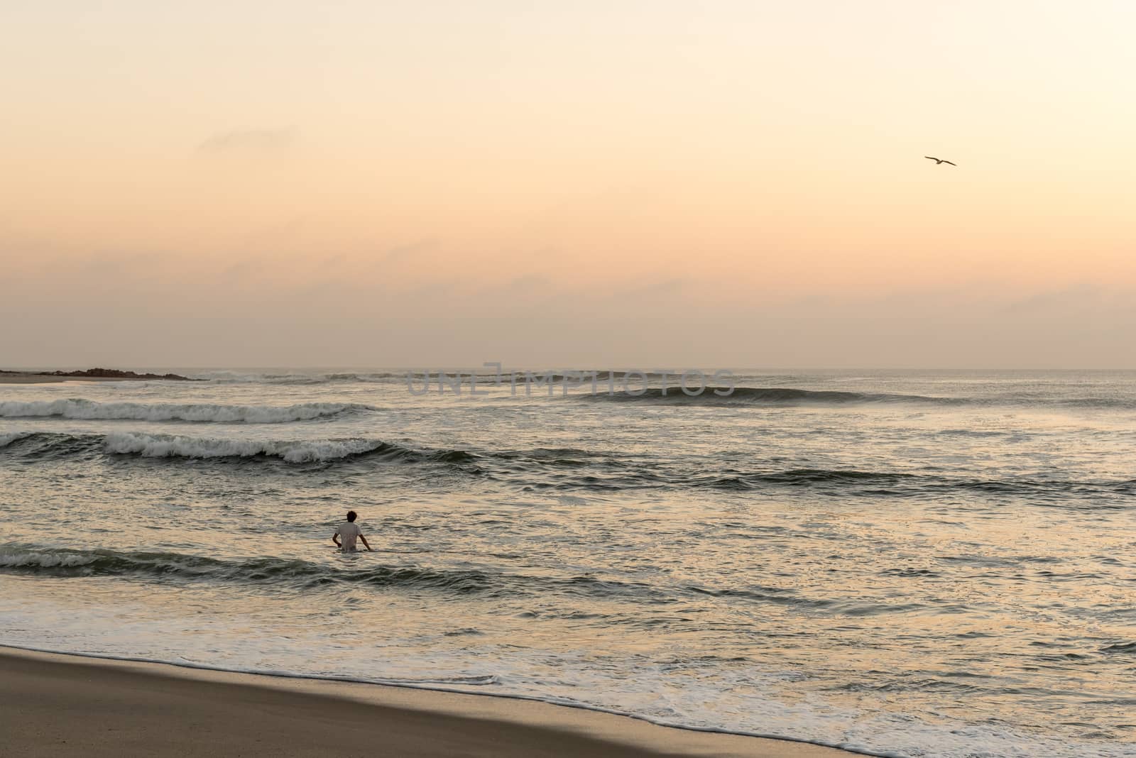 A tourist swimming in the Atlantic Ocean after sunset at Cape Cross on the Skeleton Coast of Namibia