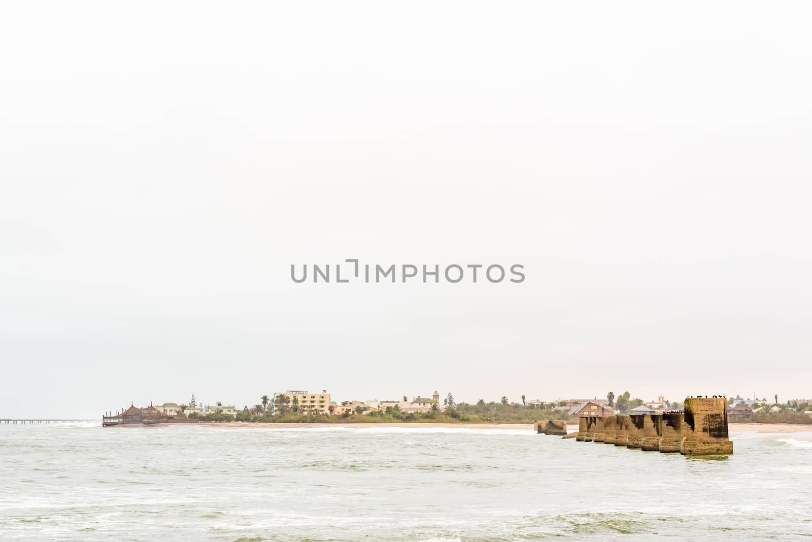 Pillars of the old railroad bridge over the mouth Swakop River with part of Swakopmund in the back
