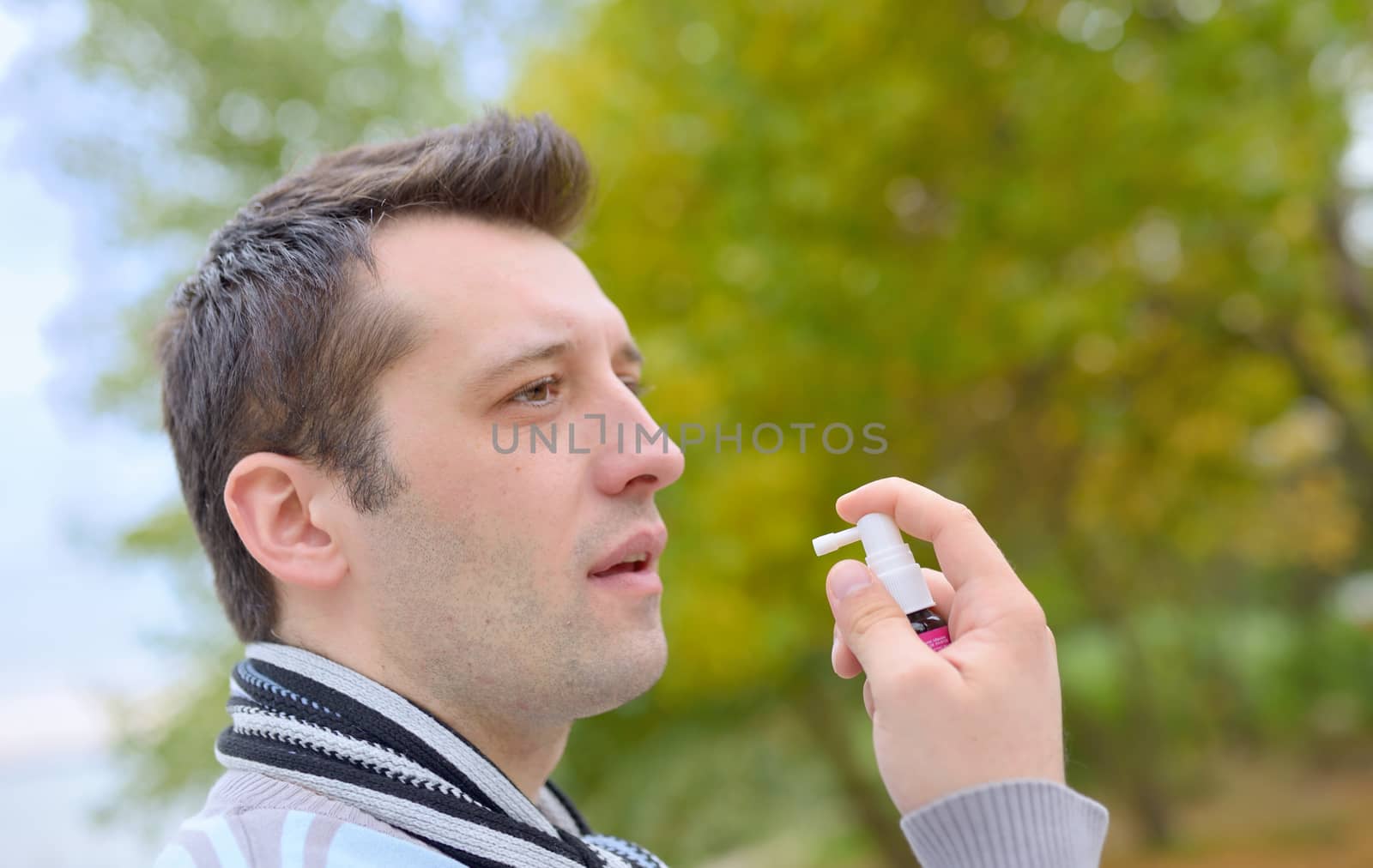 Man spraying with nasal spray in autumn time