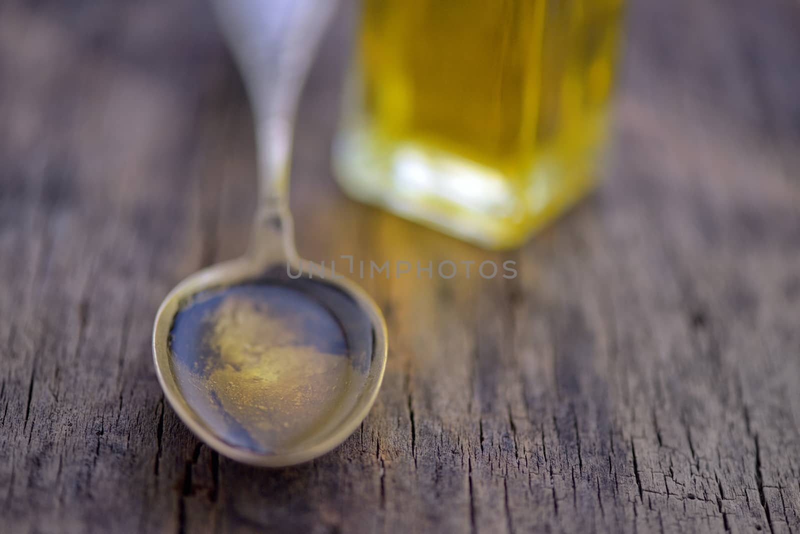 Spoon full of olive oil on wooden table