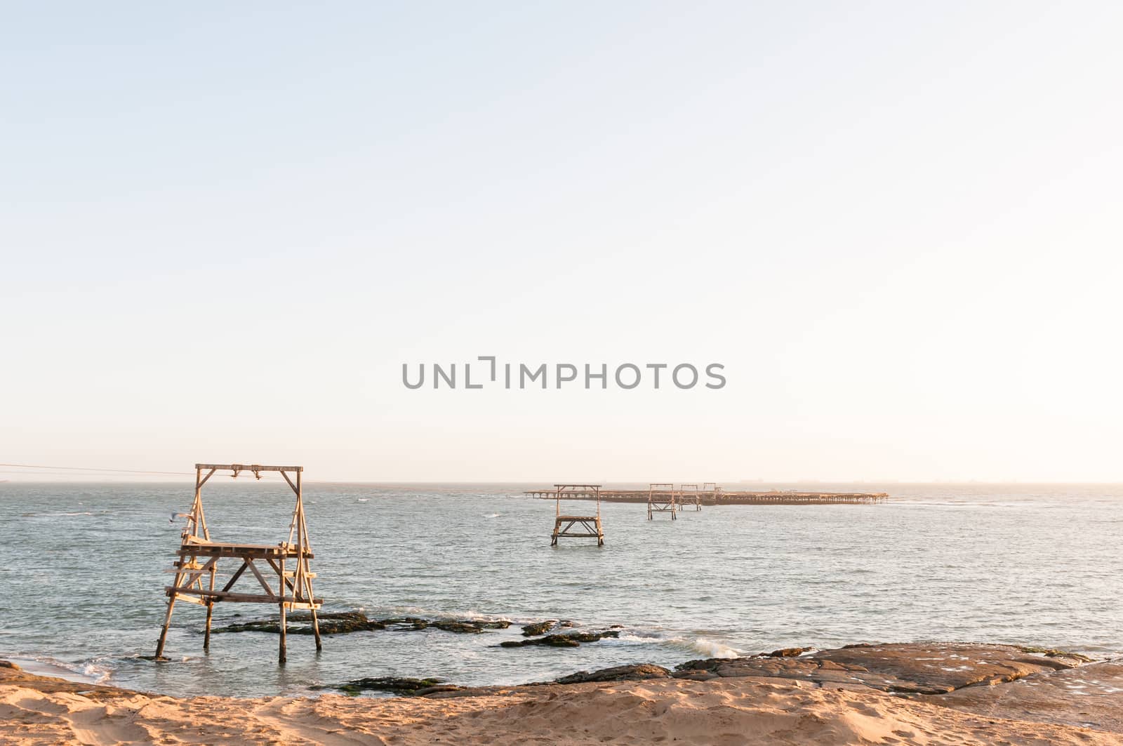 A guano island at sunset with a cableway connecting it to the mainland near Longbeach in the Namib Desert on the Atlantic Coast of Namibia