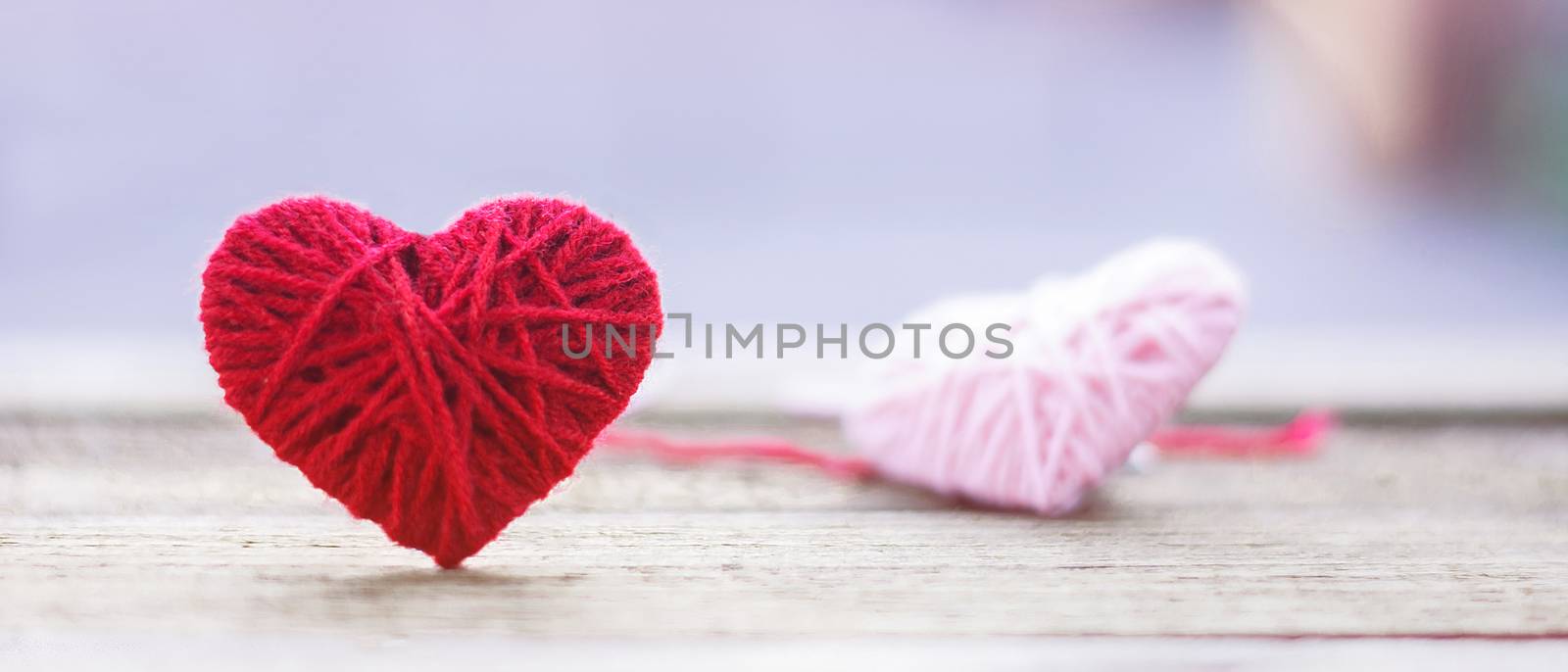 red knitting wool in shape of heart on vintage wooden with bokeh soft light background