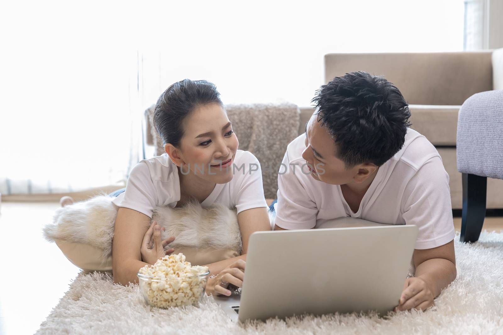 Young Asian Couples using laptop together in bedroom of contemporary house for modern lifestyle concept