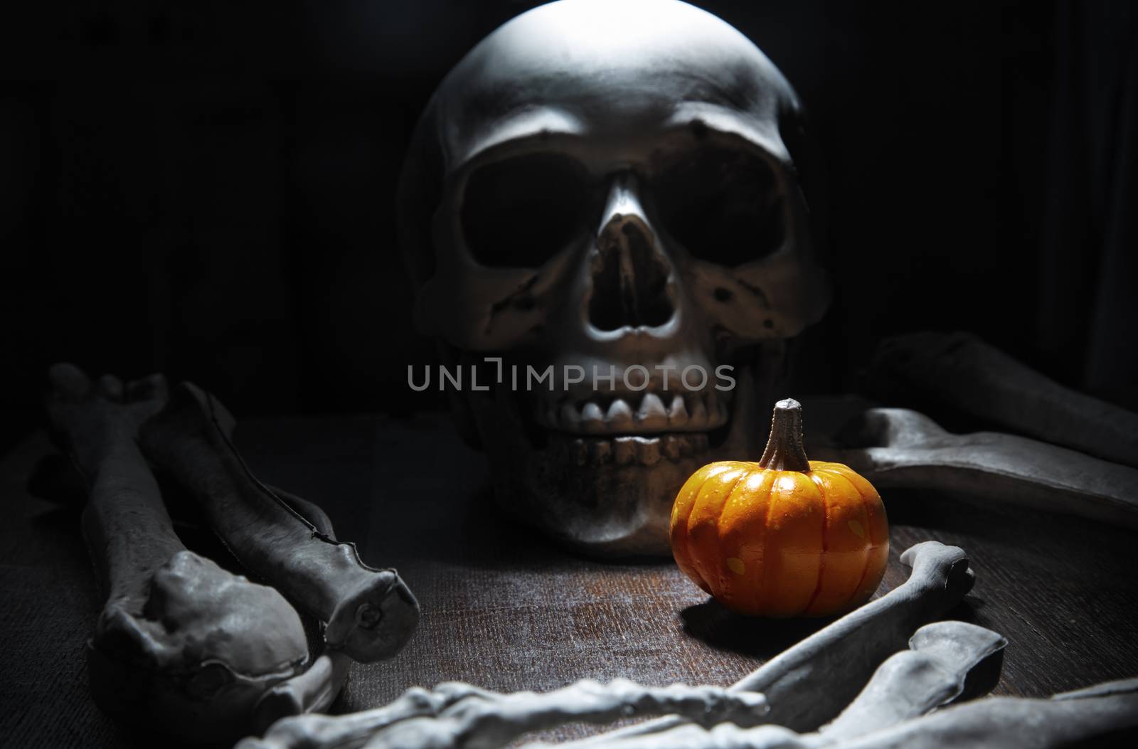 Human bones and skull on the table with Halloween pumpkin