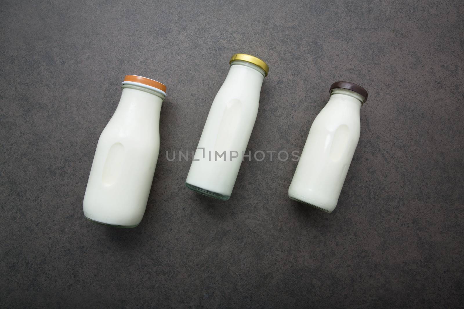 Milk bottle on dark stone background. Top view with copy space.