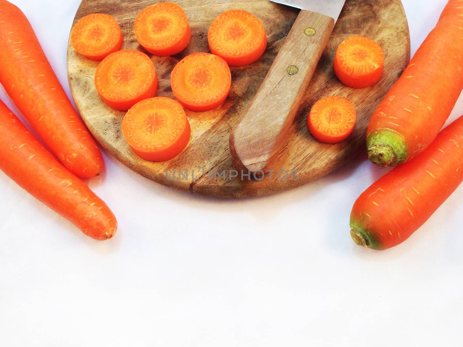 Carrot and cut pieces isolated with wooden cutting board and knife on white background by Bowonpat