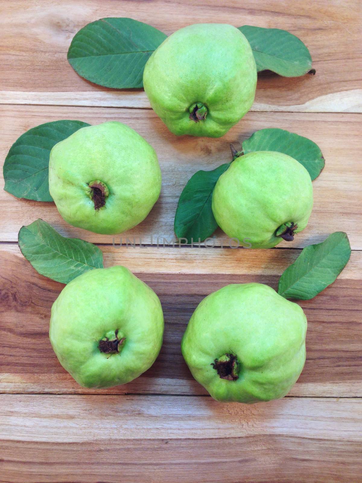 Five green guava on wooden table