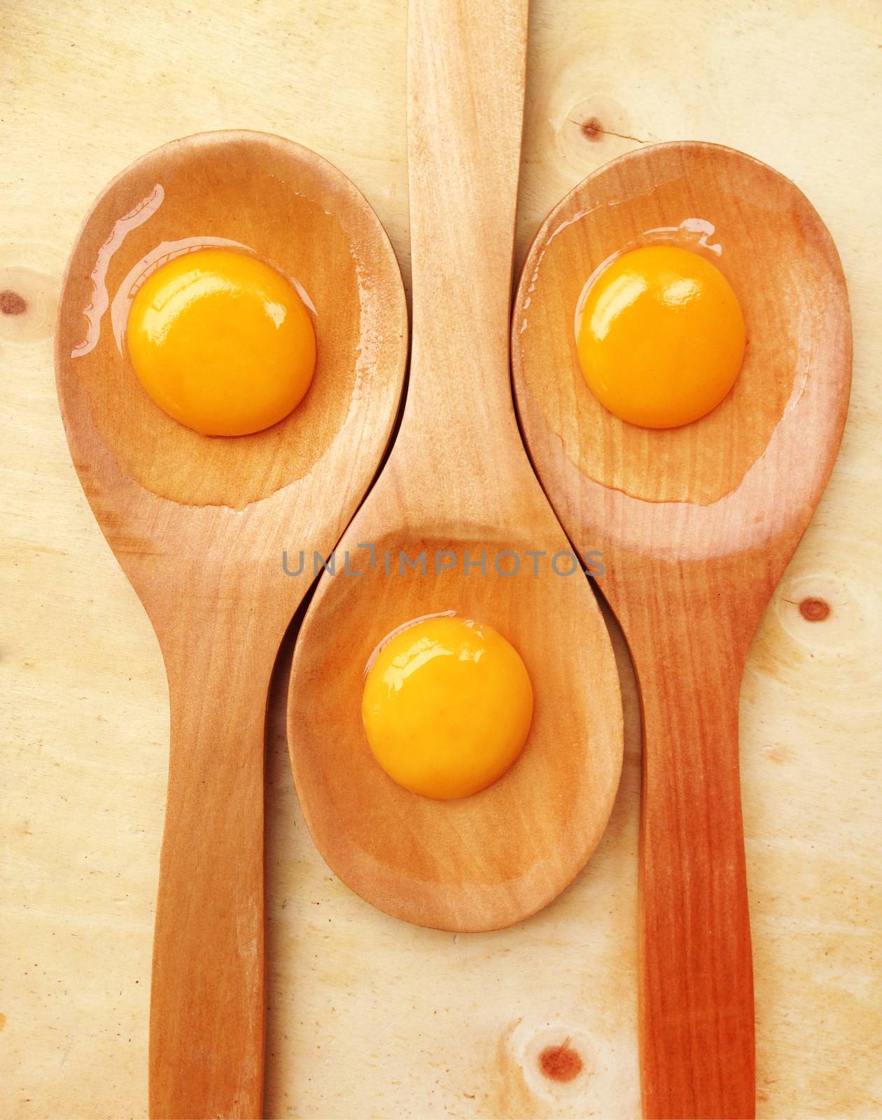 Eggs on wooden spoon on wooden background