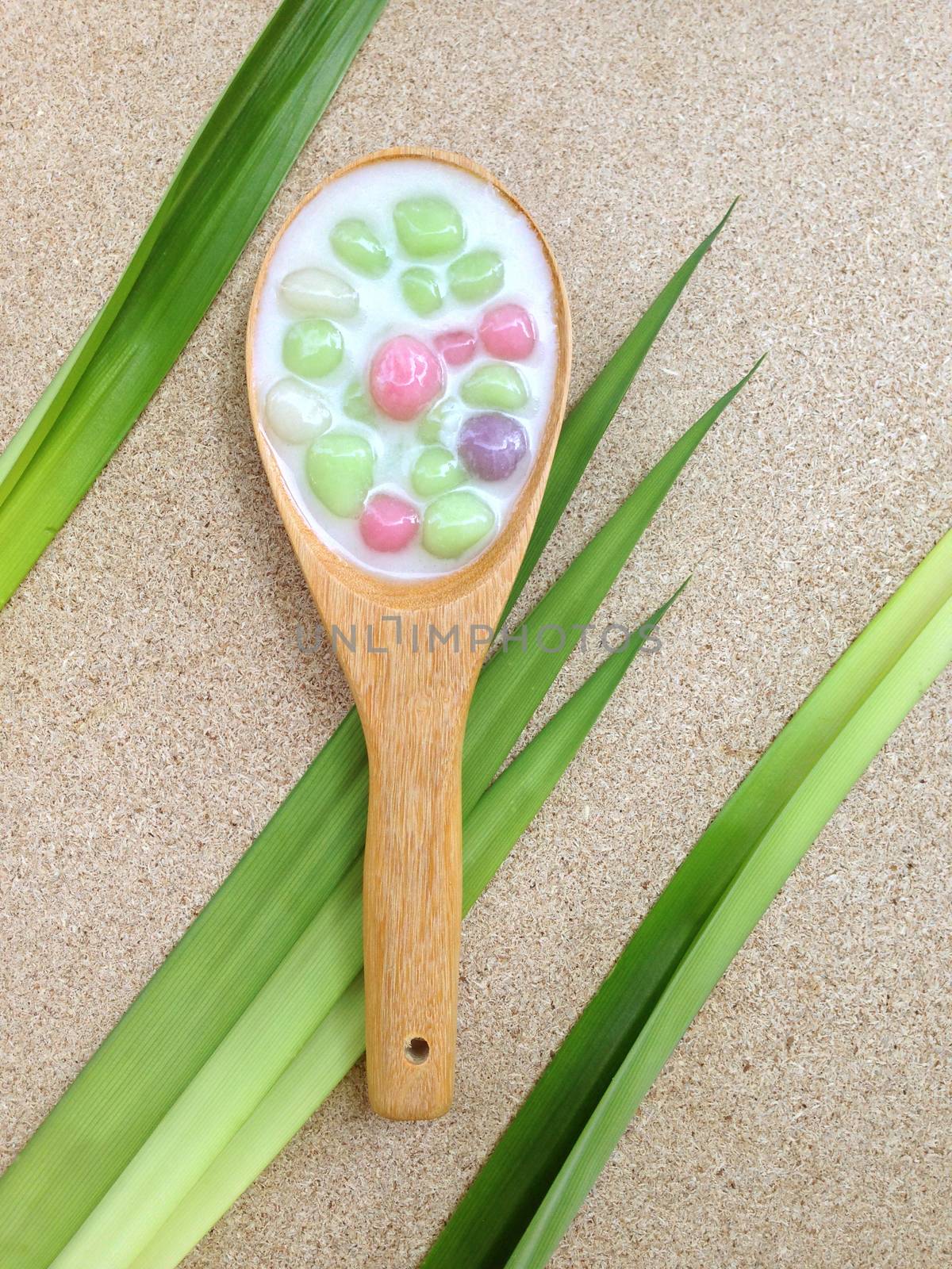 Dumplings in coconut cream in wooden spoon with fragrant pandan on plywood background