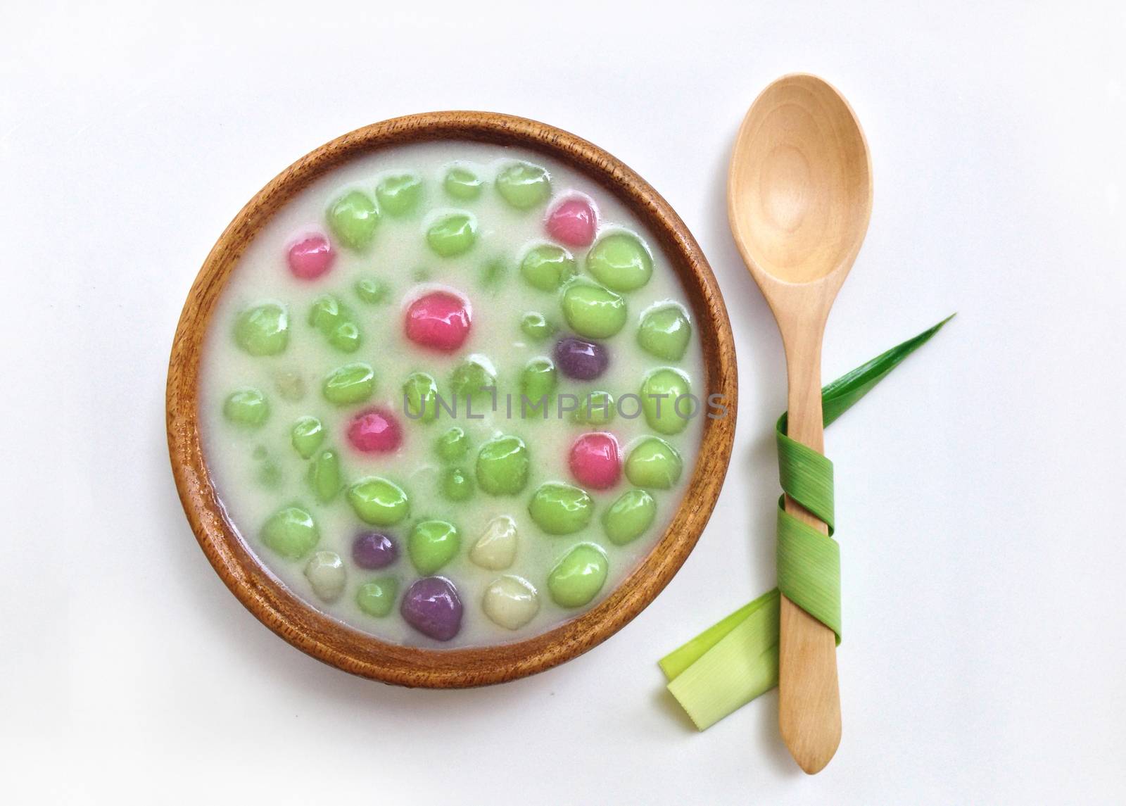 Dumplings in coconut cream in wooden bowl and wooden spoon with fragrant pandan on white background