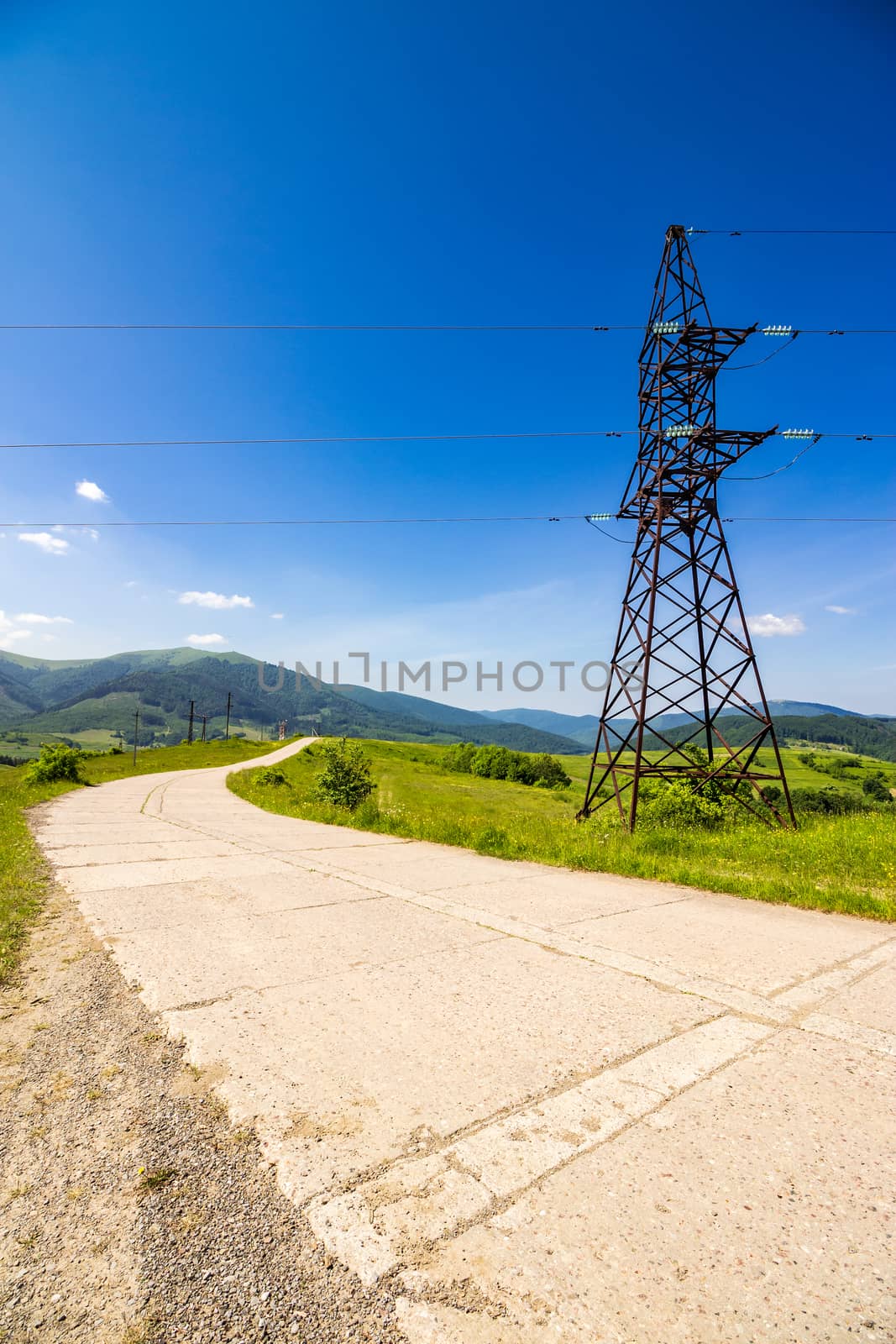 High voltage electric power lines tower near the road in mountains