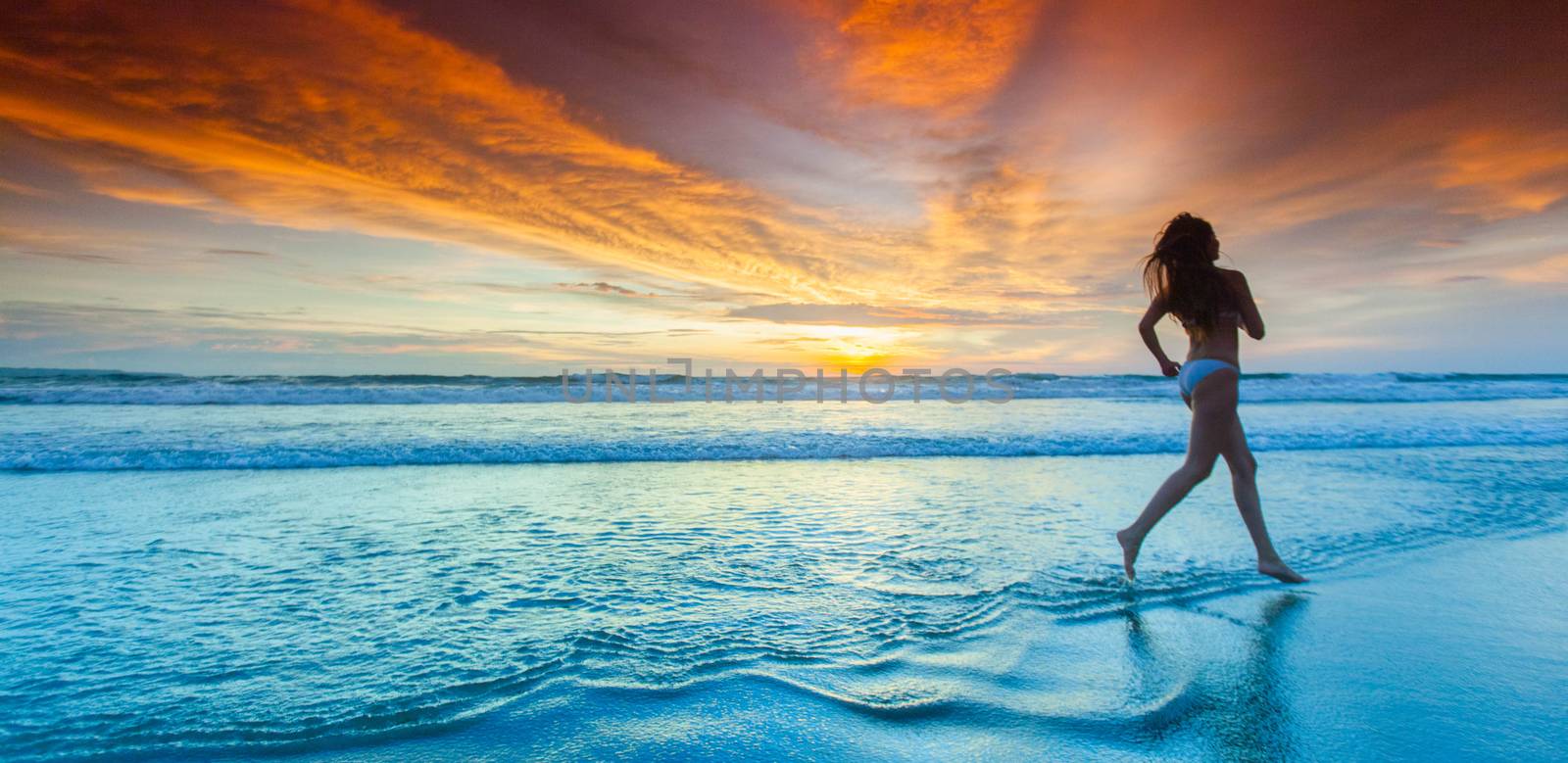 Woman in bikini running on the beach at sunset. Bali island, Indonesia