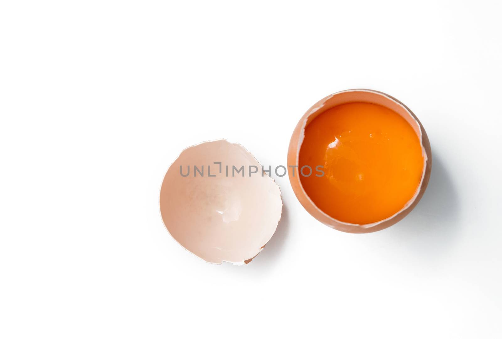 egg yolk in egg shell, cracked egg white isolated on white background