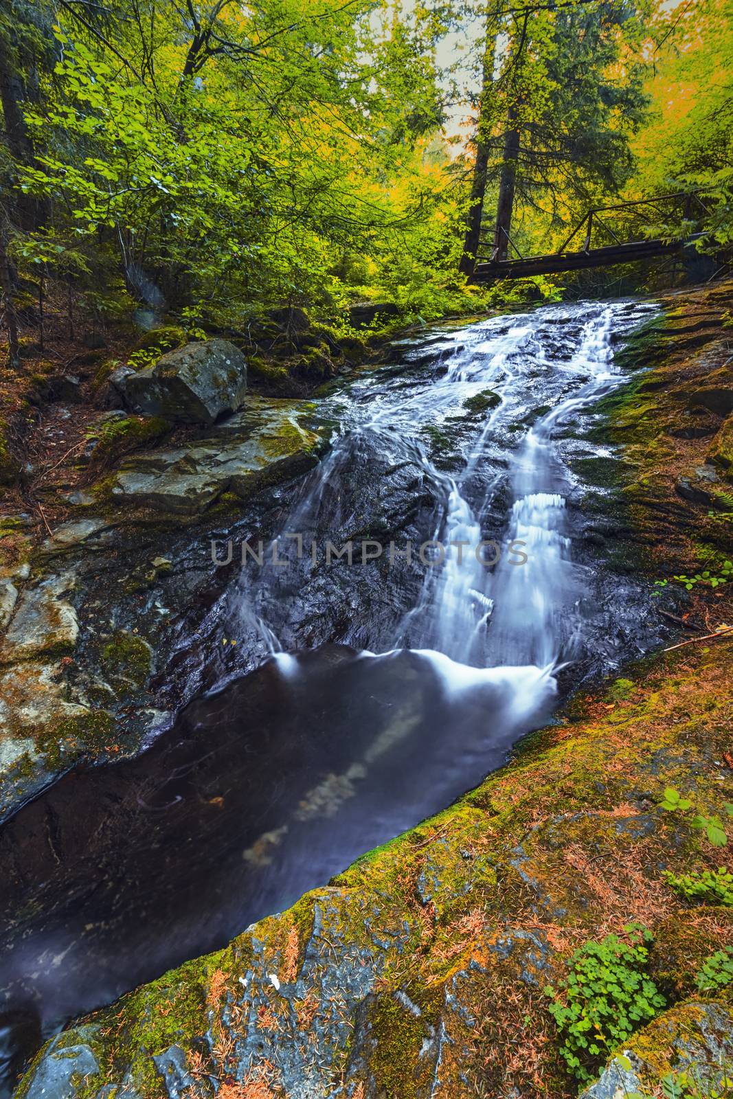 Autumn view of a small waterfall in the mountain . Long exposure