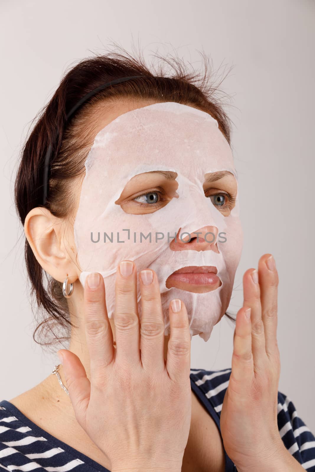 ordinary middle-aged housewife woman with cosmetic sheet mask on her face